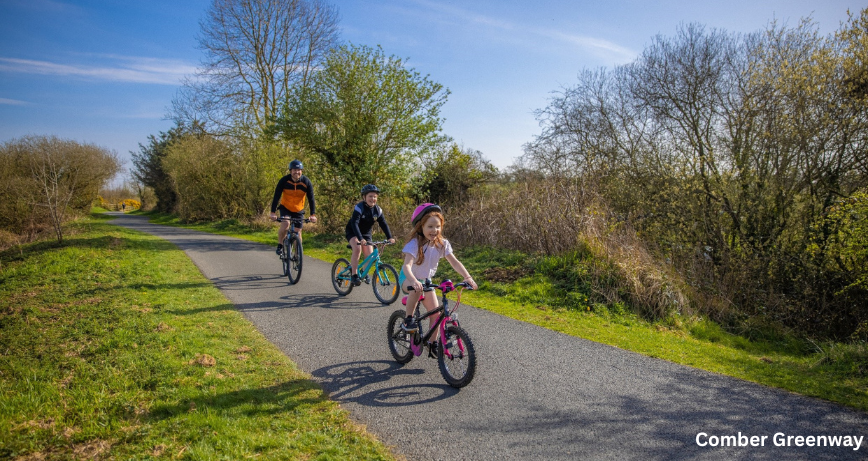 An adult and two children cycling along the Comber Greenway